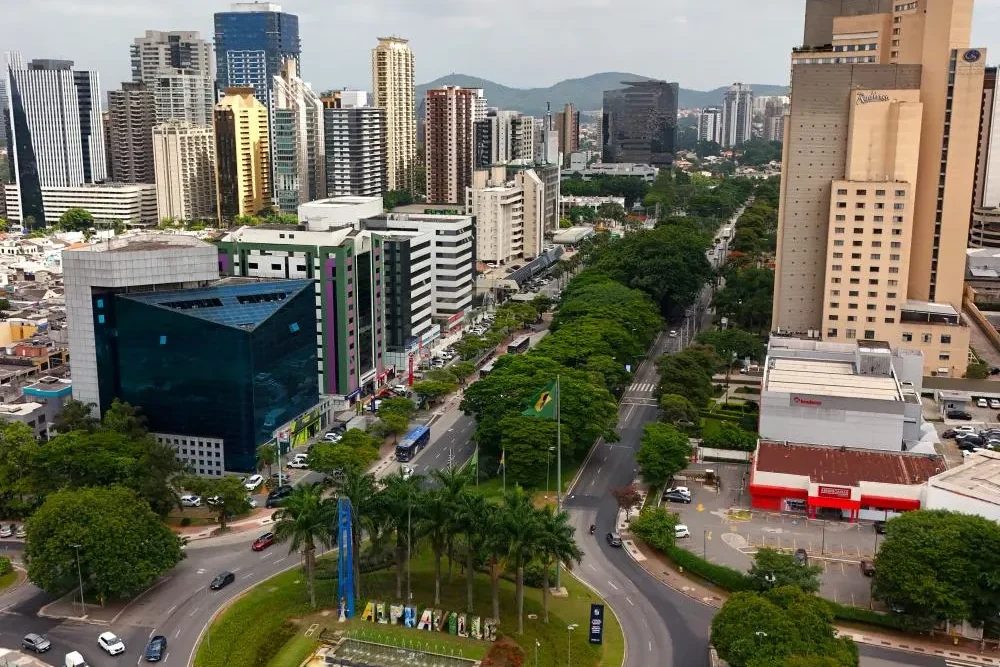 Vista aérea de Alphaville em Barueri, com as torres corporativas, a avenida arborizada e o letreiro no canteiro central