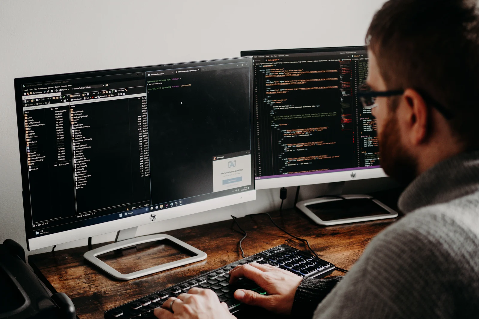 Desenvolvedor programando em estação de trabalho com dois monitores, um deles com o editor de código aberto