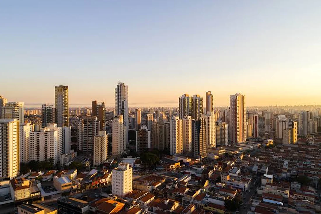 Skyline de Ribeirão Preto ao entardecer, com os edifícios altos recortados contra o céu alaranjado